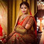 Stunning Indian Bride Dressed In Bright Red Colored Lehanga With Full Makeup And Wearing Heavy Jewellry.